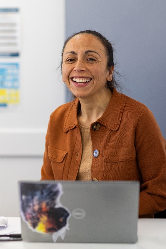 Woman smiling while sitting at a desk with a laptop